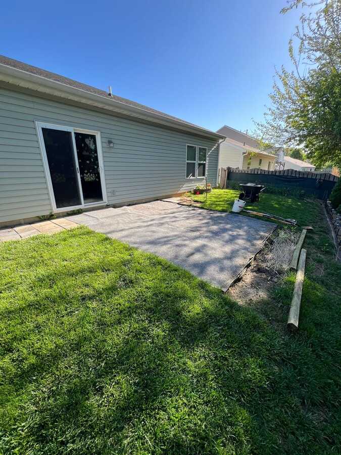 Before: worn concrete slab patio behind a gray-sided house